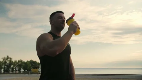 Bodybuilder in sportswear standing and drinking water from a sports shaker Stock Footage 200118002