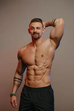 A bodybuilder is standing with one hand behind his head Stock Photos