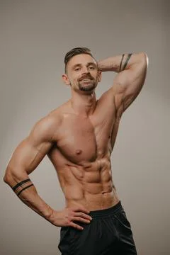 A bodybuilder is standing with one hand on his hip and another behind his hea Stock Photos