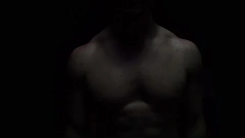 The bodybuilder stands in a dark room and slowly looks around Stock Footage 130301201