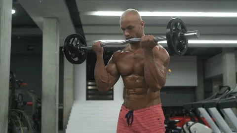 Bodybuilder strong man pumping up biceps muscles Video stock 131381122