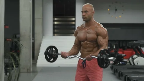 Bodybuilder strong man pumping up biceps muscles Video stock 131384297