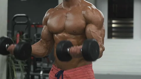 Bodybuilder strong man pumping up biceps muscles Video stock 131386000