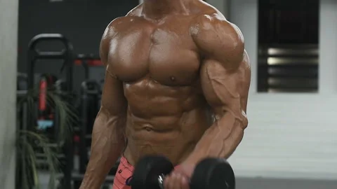 Bodybuilder strong man pumping up biceps muscles Video stock 131386152