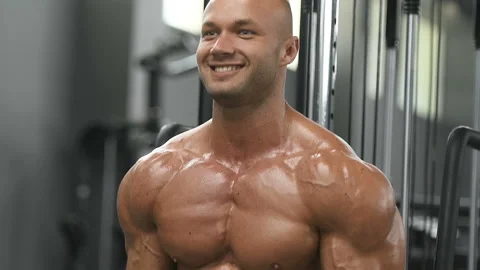 Bodybuilder strong man pumping up biceps muscles Video stock 131386361