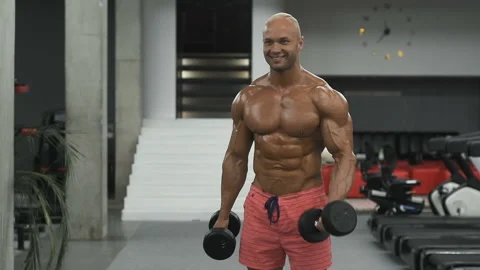 Bodybuilder strong man pumping up biceps muscles Video stock 131386901