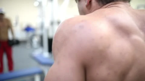 Bodybuilder swings back muscles using dumbbells Stock Footage 57243855