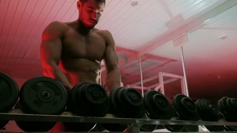 Bodybuilder takes dumbbells off the shelf Stock-Footage 75807701