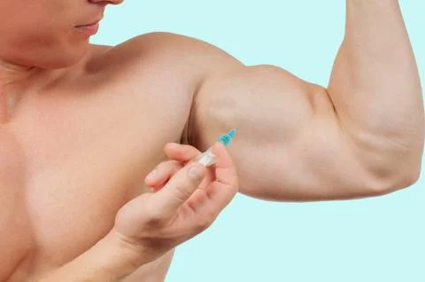 Bodybuilder taking steroids injection in arm on blue background. Stock-Fotos