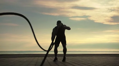 Bodybuilder training outdoors doing an exercise with battle ropes against  Stock Footage 200118391