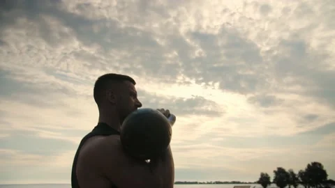 Bodybuilder training outdoors doing an overhead kettlebell pushing exercise. Stock Footage 200118354