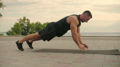 Bodybuilder training outdoors doing push-ups with hands clapping. Sky Sunset Stock Footage 200118464