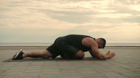 Bodybuilder training outdoors, doing stretching exercises against a backgrou Stock Footage 200118501