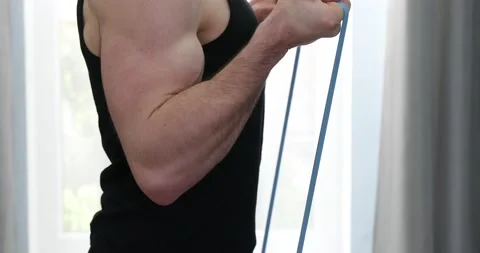 Bodybuilder is training with rubber tapes in apartment, strength workout for  Stock Footage 152835685