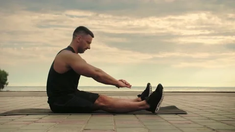 Bodybuilder is training for a stretching exercise on a playground Stock Footage 200118012
