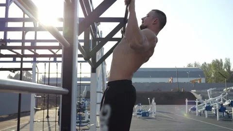 A bodybuilder trains outdoors, does pull-ups. Outdoor fitness training. Stock Footage 287580758
