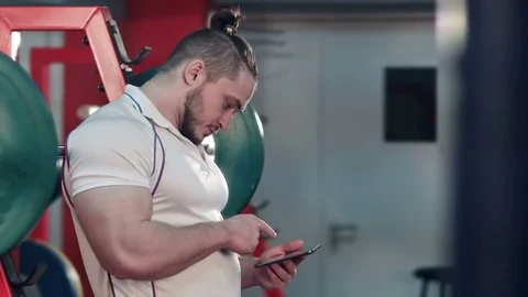 Bodybuilder using digital tablet to track his workout progress in gym Видео 74116621