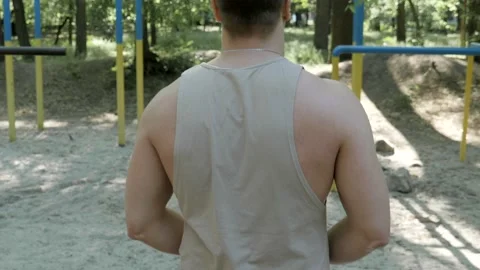 Bodybuilder walking towards bars outdoor in the park Stock Footage 130268657