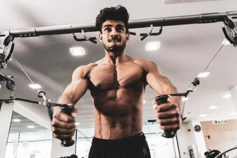 Bodybuilder Is Working On His Chest With Cable Crossover In Gym. Scream for Stock Photos