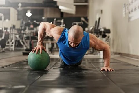 Bodybuilder working out and doing push upsat the gym while Stock Photos
