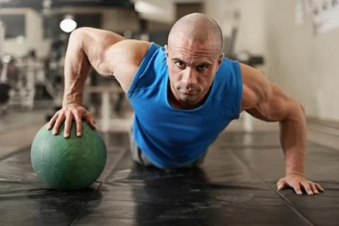 Bodybuilder working out and doing push upsat the gym while Stock Photos