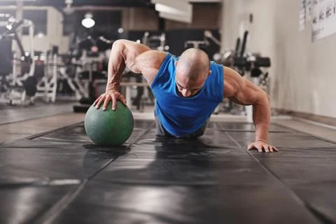 Bodybuilder working out and doing push upsat the gym while Stock Photos