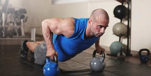 Bodybuilder working out and doing push upsat the gym while Stock Photos