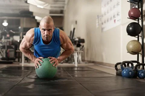 Bodybuilder working out and doing push upsat the gym while Stock Photos