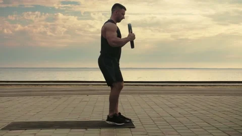 Bodybuilder working out on the beach doing lunges against a backdrop of the  Stock Footage 200118694