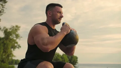 Bodybuilder working out on the beach doing lunges against a backdrop of the  Stock Footage 200118698