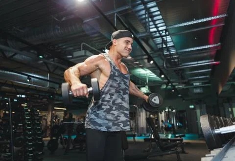 Bodybuilder working out with dumbbell weights at the gym man bodybuilder doin Stock Photos