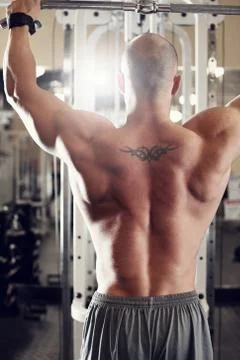 Bodybuilder working out at the gym while using fitness machine Stock Photos