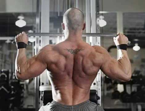 Bodybuilder working out at the gym while using fitness machine Stock Photos