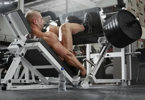Bodybuilder working out at the gym while using fitness machine Stock Photos