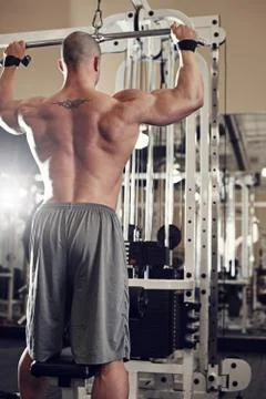Bodybuilder working out at the gym while using fitness machine Stock Photos