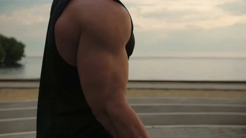 Bodybuilder working outdoors performs dumbbell one-handed lifting. Stock Footage 200118759