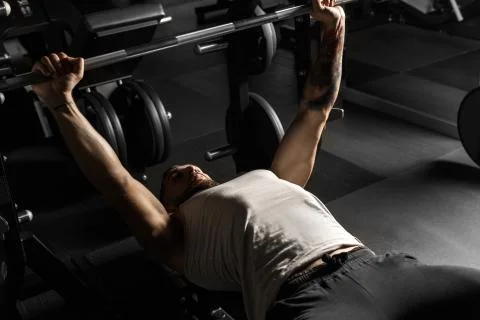 Bodybuilding. Bearded man lying doing bench press at gym with barbell Foto stock