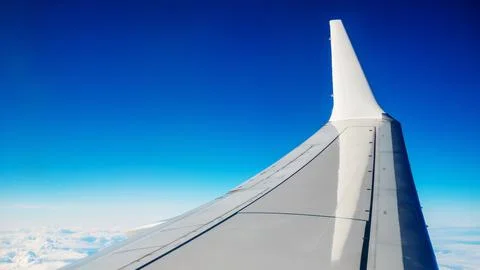 Boeing 737 MAX 8 White Wing Over White Air Clouds And Clear Blue Sky. Stock Photos