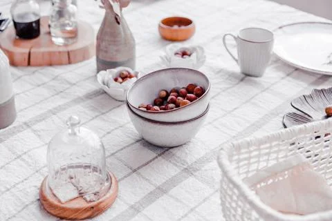 Bohemian style dining table featuring ceramic bowls with nuts, glass cloche Photos