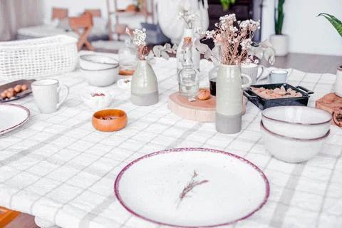 Boho interior design featuring a dining table set with ceramic plates Stock Photos