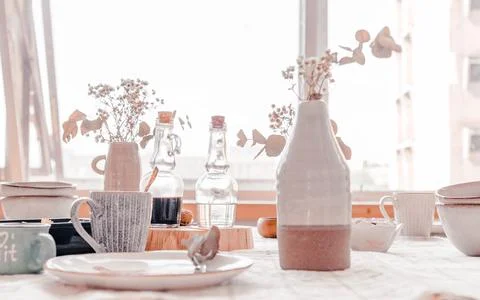Boho interior design table setting featuring ceramic dishes, glass bottles, and Foto stock