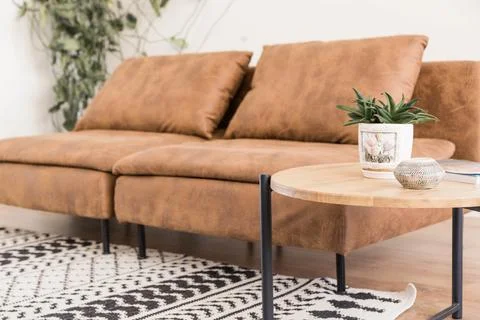 Boho style interior featuring a brown leather sofa, round wooden coffee table Stock Photos