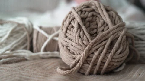 Boho-style wool threads lie on the bed, a woman's hand takes a ball. Suitable Stock Footage 152976316