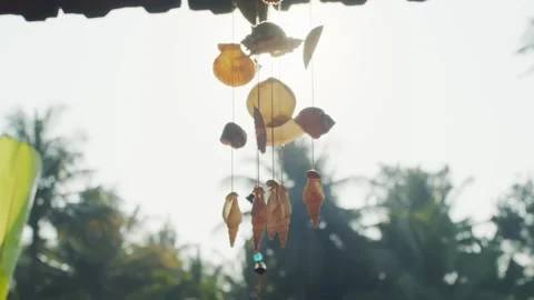 Boho wind chime trembling on wind outdoors on white sky background slow motion Stock Footage 130230591