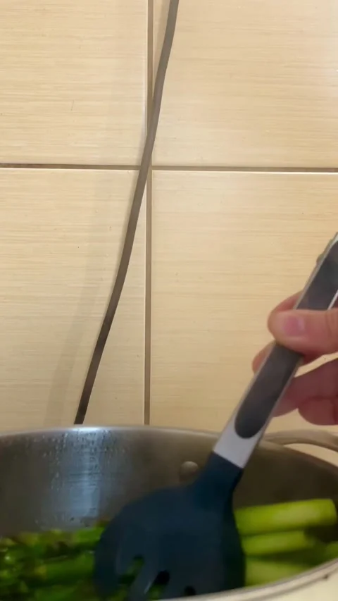 Boil asparagus. blanching young green asparagus with tongs Stock Footage 310409853