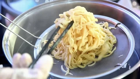 Boil the noodles in a hot pan while stirring Stock Footage 300621206