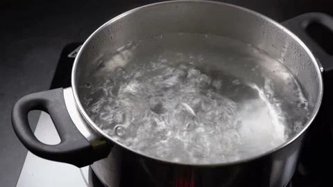 Boil water in a pot on dark background, Stock Video