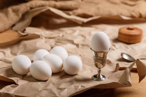 Boilde eggs and one egg in silver egg cup with spoon and salt pot on paper Stock Photos