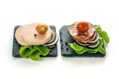 Boiled and salami sausage eats on a black slate plate with lettuce Stock Photos