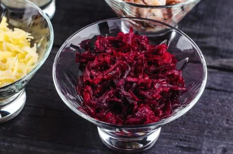 Boiled beet shredded in a transparent deep dish on a wooden black background. Stock Photos